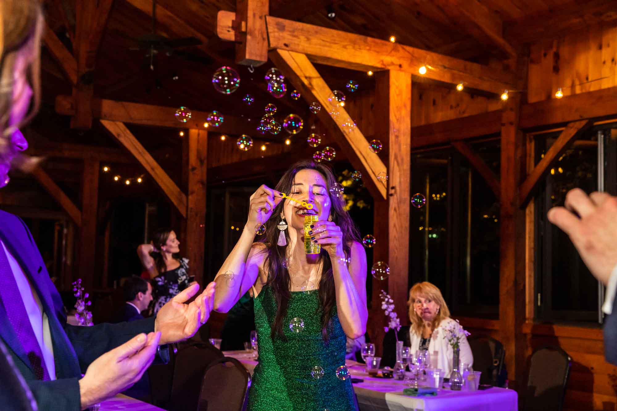 adult wedding guests is blowing bubbles all over the dance floor at this fun wedding! these are the moments that a photojournalist who photographs weddings will not miss.